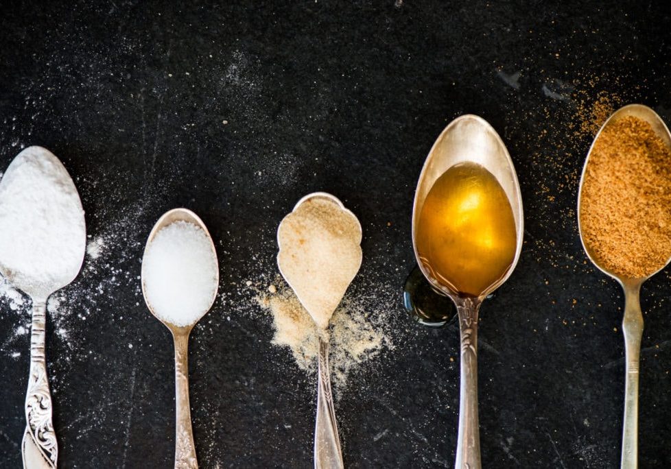 Different Kinds of Sugar in the Spoons, such as coconut sugar, pure cane sugar, icing sugar, agave syrup, dark brown soft sugar, golden caster sugar, demerara cubes