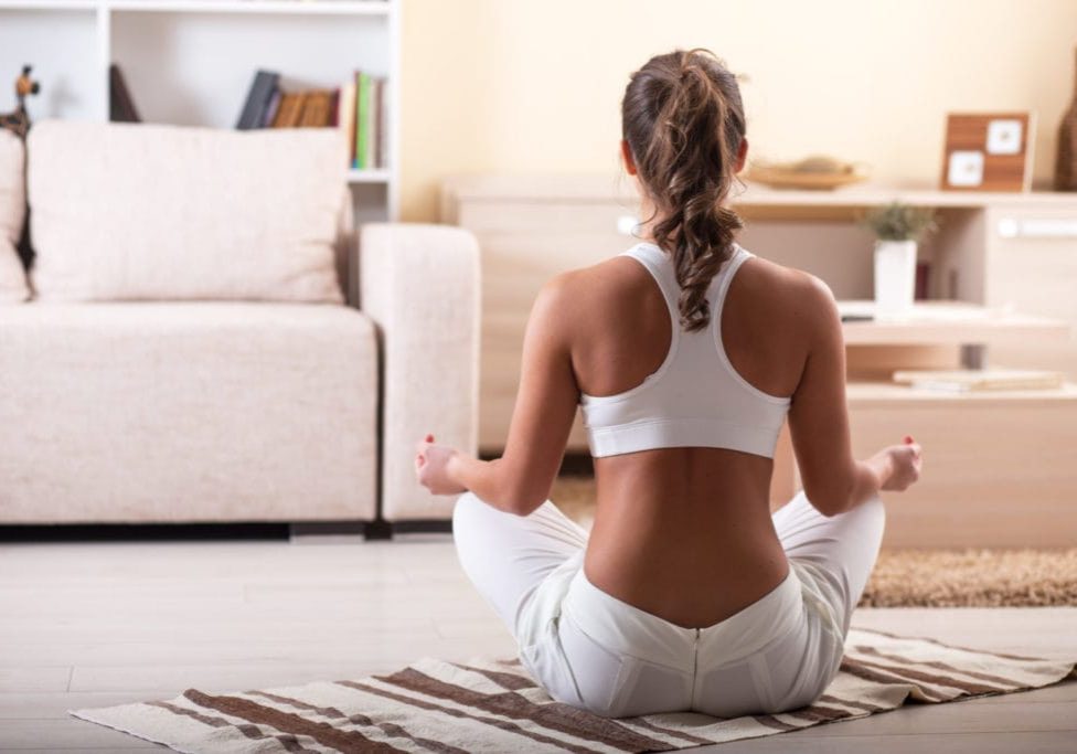 Young female meditate in her living room.